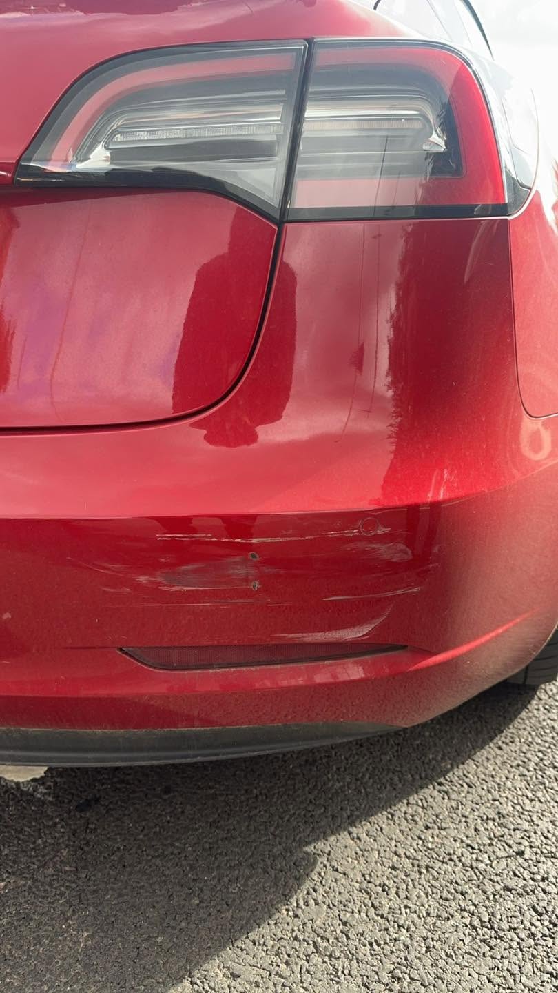 Red Tesla with scuffs to the rear bumper